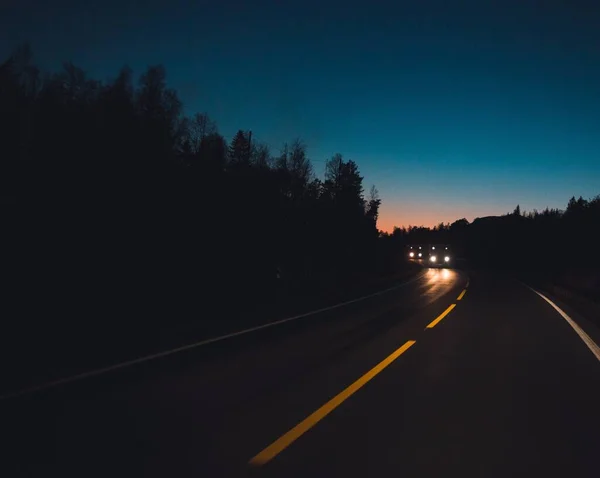 Tiro horizontal de carros na estrada com um monte de árvores à noite — Fotografia de Stock