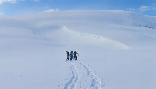 Группа людей, прогуливающихся в горах, покрытых снегом под красивым голубым небом — стоковое фото