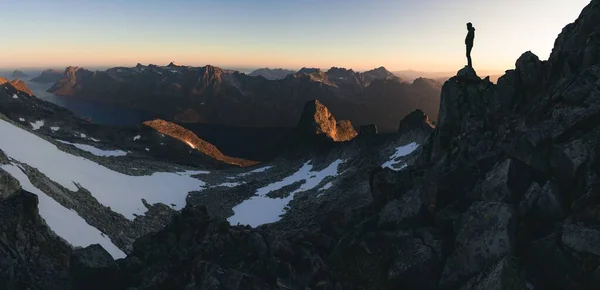 Plan large d'un mâle debout sur un rocher sur une haute montagne profitant de la belle vue pendant le lever du soleil — Photo