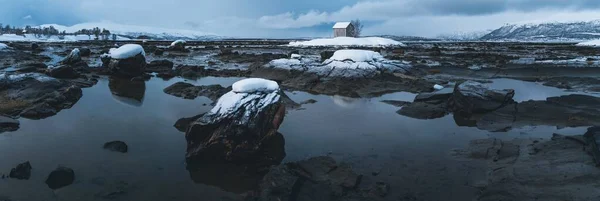 水の中の多くの岩の広いショットと曇った空の下で孤立した家 — ストック写真