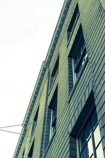 Balança vertical de baixo ângulo de um edifício cinzento velho com o céu branco no fundo — Fotografia de Stock