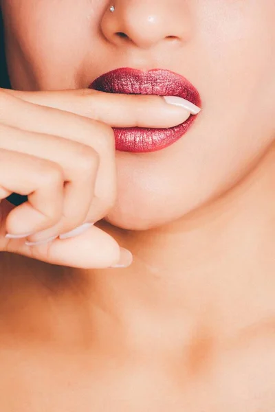 一张女性用红色口红咬指尖的垂直特写照片 这对一篇关于化妆品的文章很有帮助 — 图库照片