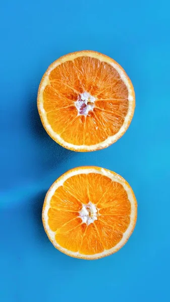 蓝色表面上橙色半边的垂直特写镜头- -完美的背景 — 图库照片