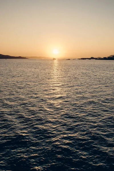 Vertikale Aufnahme des Meeres, das das Sonnenlicht reflektiert, mit einem schönen Himmel im Hintergrund — Stockfoto