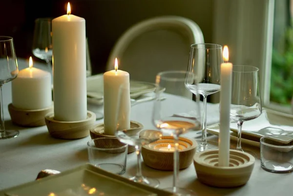 Fotografie de aproape a unei mese cu lumânări albe aprinse și pahare de vin. Perfect pentru piesa de design de masă . — Fotografie, imagine de stoc