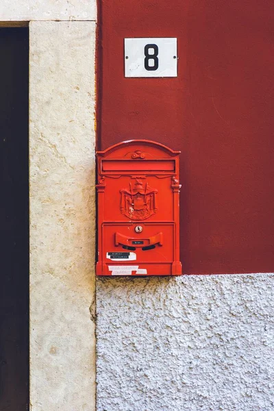 Vertikale Nahaufnahme eines roten Briefkastens mit eingraviertem Stadtwappen und einer Haustafel darüber — Stockfoto