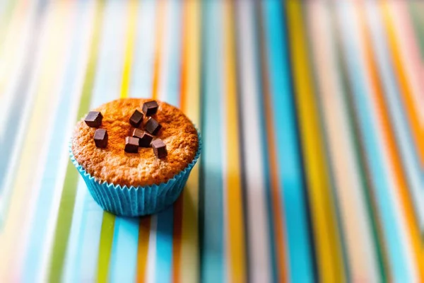 Gros plan horizontal d'un cupcake avec garnitures au chocolat sur une surface colorée — Photo