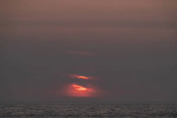 Coucher de soleil à couper le souffle sur l'océan avec un ciel clair et un soleil rouge vif — Photo