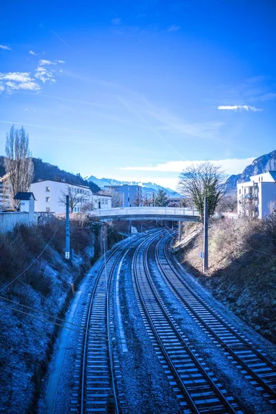 Bulutlu bir gökyüzünün altında, açık bir kış gününde, bir kasabanın ortasındaki köprünün altında üç yönlü demiryolu. — Stok fotoğraf