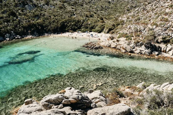 Alto ángulo de tiro de mar de agua clara con la gente en la orilla rodeada de montañas — Foto de Stock