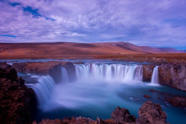 A horizontal shot of Godafoss Falls, out of Akureyri, Iceland under the breathtaking cloudy sky clipart