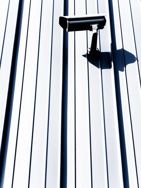 Fotografía vertical de una cámara de seguridad sobre una superficie blanca durante el día — Foto de Stock