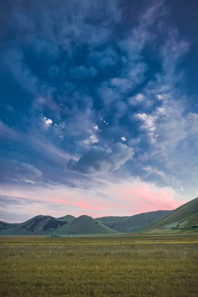 Függőleges lövés a lélegzetelállító színes őrült felhők és egy zöld hegylánc Norcia, Olaszország — Stock Fotó