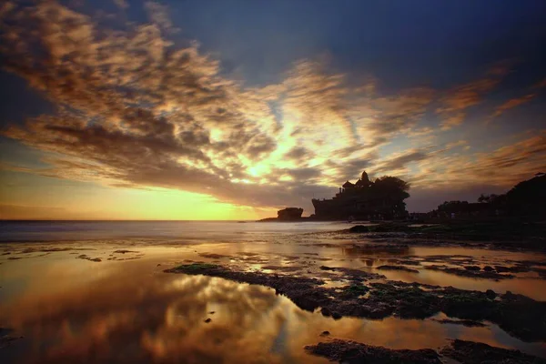 Horizontální záběr chrámu Tanah lot u vody pod krásnou zamračenou oblohou na Bali v Indonésii — Stock fotografie