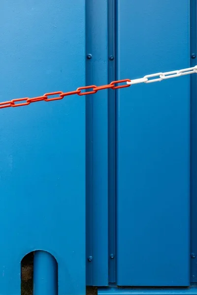 Vertikal bild av en blå metalldörr och en röd och vit kedja - perfekt för en cool tapet — Stockfoto