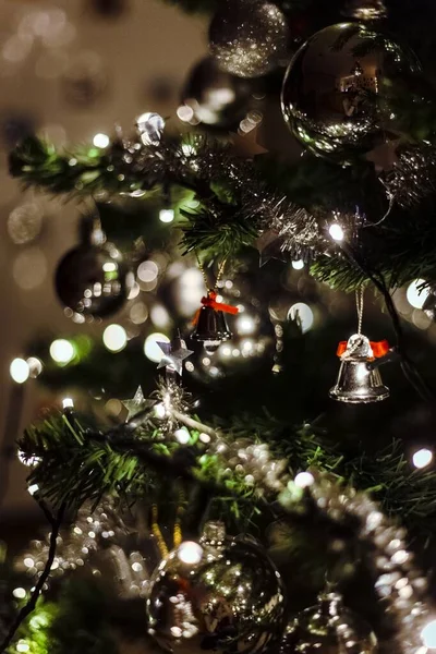 Primer plano vertical de hermosas bolas de plata y campanas colgando de un árbol de Navidad — Foto de Stock
