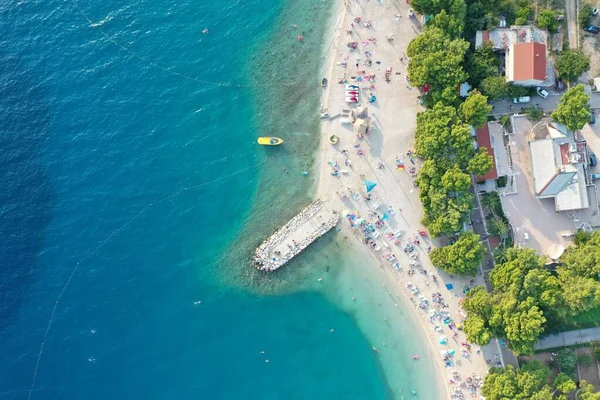 Aerial shot of a beat on the water near the shore with building st daytime in Makarska, Croatia — Stock Photo, Image