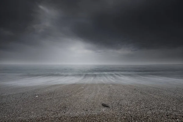 Όμορφη ταπετσαρία μιας βοτσαλωτής παραλίας κάτω από ένα γκρίζο συννεφιασμένο ουρανό. Μεγάλη για οθόνη επιφάνειας εργασίας — Φωτογραφία Αρχείου
