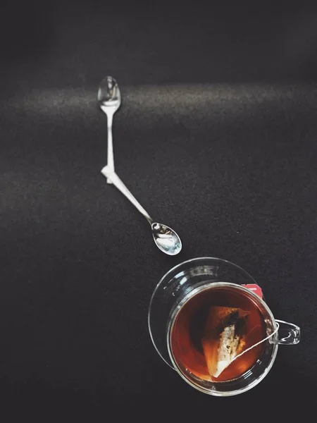 お茶のカップと時計のように配置された2つのスプーンの高角度ショット-時間管理コンセプト — ストック写真