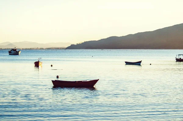 Красивый снимок пустых лодок на море с горами и ярким небом на заднем плане — стоковое фото