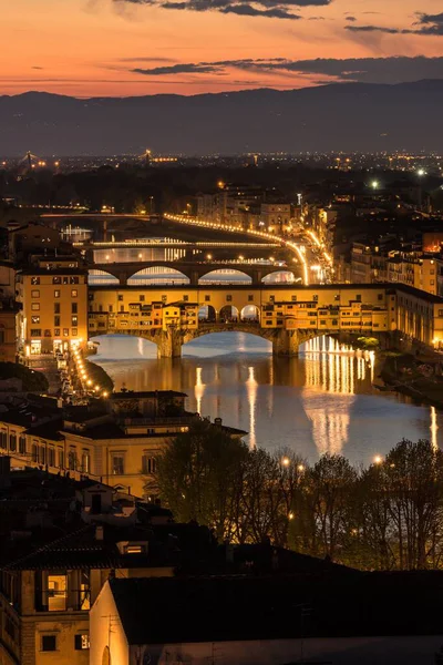 Ponte Vecchio köprüsünün gece vakti bir sürü ışıkla dikey görüntüsü. — Stok fotoğraf
