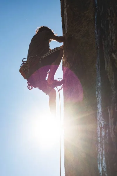 Captura vertical de ángulo bajo de una persona subiendo la colina con el fondo de rayos de sol brillantes —  Fotos de Stock