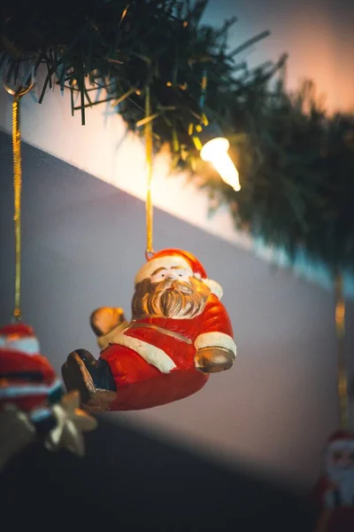 Tiro foco seletivo vertical de um ornamento de Papai Noel pendurado em uma árvore de Natal — Fotografia de Stock