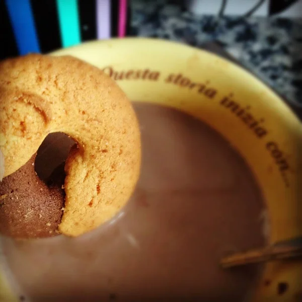 Closeup shot of a biscuit in a cup filled with chocolate milk with 'this story begins with...' print — Stock Photo, Image