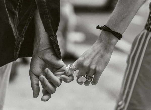 Grayscale shot of a person 's hand with a heart-shaped ring holding another person' s hand. — Foto de Stock