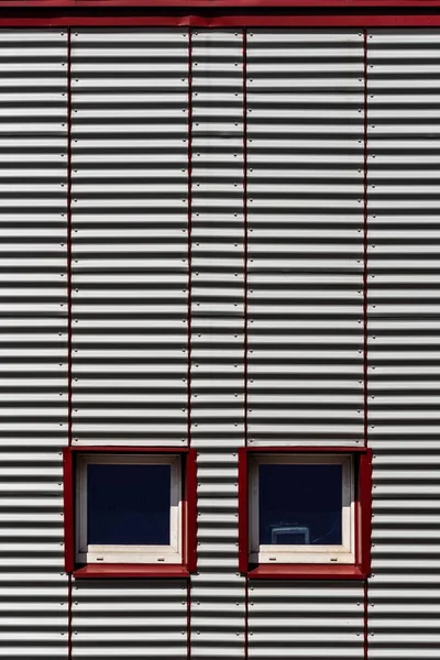 Tiro vertical de uma parede de metal cinzento com janelas fechadas durante o dia — Fotografia de Stock