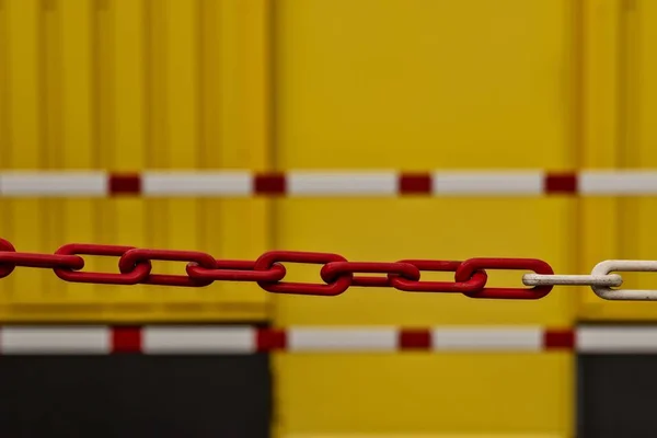 Horizontal shot of a red metal chain on a blurred yellow background - great for a cool background