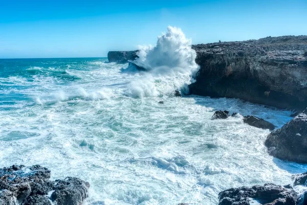 Foto horizontal de hermosas olas marinas y colinas rocosas bajo el cielo azul claro — Foto de Stock