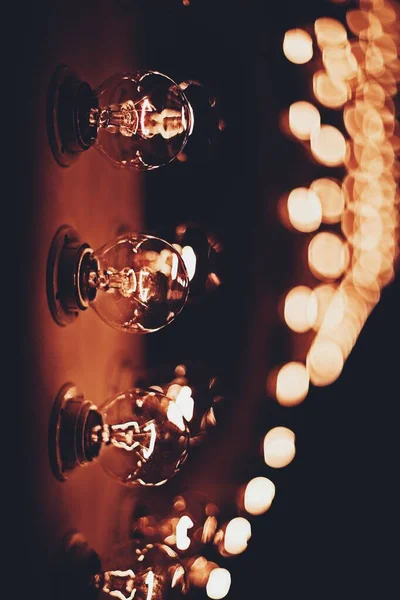 Vertical closeup shot of three light bulbs in the dark with bokeh lights in the background