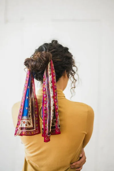 Photo verticale du dos d'une femme, cheveux noués avec un chiffon aux motifs orientaux — Photo