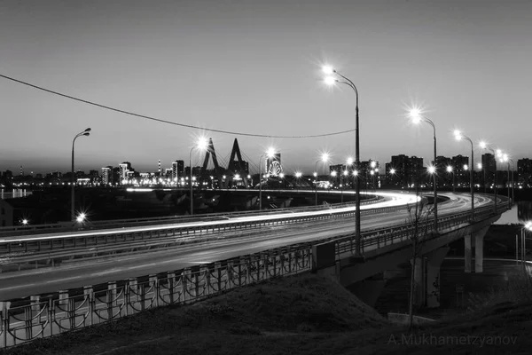 Plan horizontal en échelle grise d'une autoroute avec des lampadaires et de hauts bâtiments la nuit — Photo