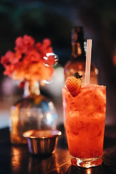 Vertikale Aufnahme eines roten Getränks mit Strohhalmen auf dem Tisch mit verschwommenem Hintergrund — Stockfoto
