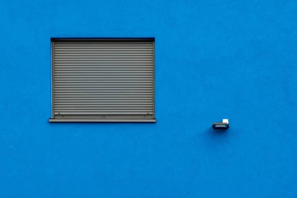 Horizontal shot of a blue wall with a grey window blind - great for a cool wallpaper or background