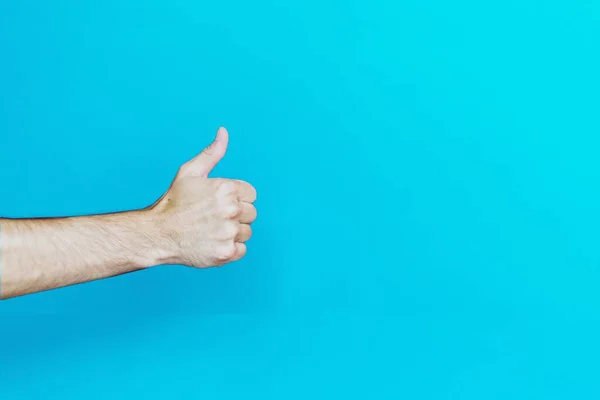 Ręka osoby pokazująca kciuki w górę na jasnoniebieskim tle - świetna na chłodne tło — Zdjęcie stockowe
