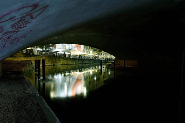 Horizontal shot of beautiful buildings reflected in the lake under a concrete bridge in Milan, Italy — Stock Photo, Image