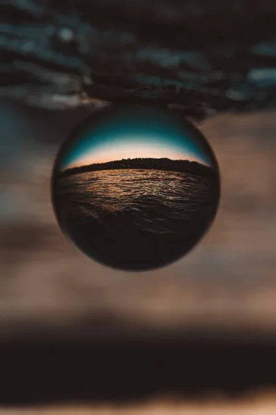Piękne pionowe zbliżenie szklanej kuli z odbiciem zapierającego dech w piersiach zachodu słońca — Zdjęcie stockowe