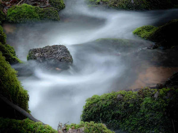 Beautiful shot of the water flowing in the middle of mossy rocks — Stock Photo, Image