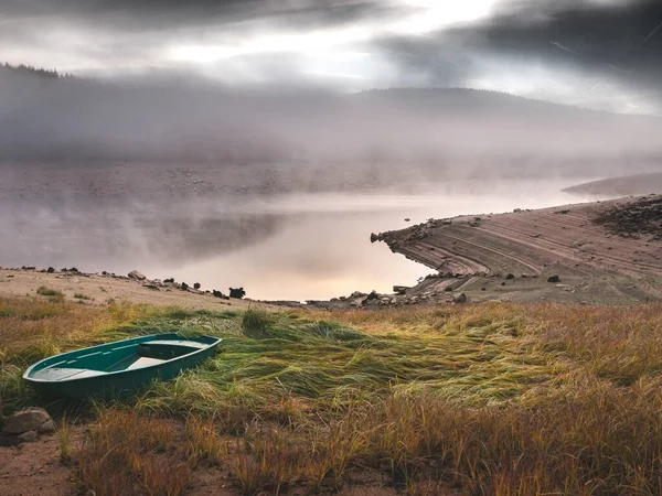 Krásný záběr zelené lodi na travnatém kopci v blízkosti moře s mlhavým pozadím — Stock fotografie