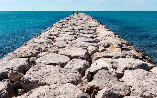 Горизонтальний знімок кам'яної доріжки на тілі води з людьми, що ходять по ній . — стокове фото