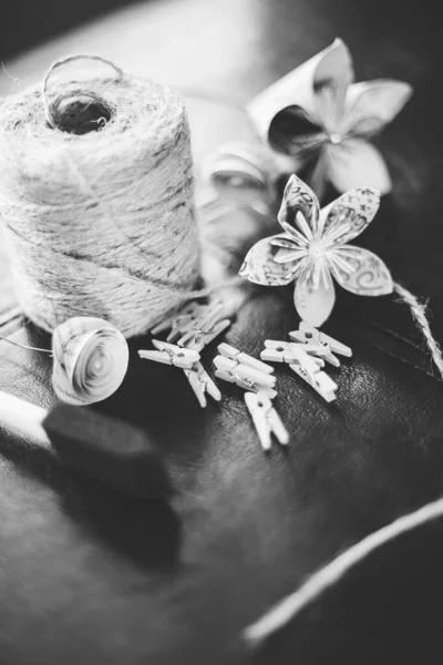 Grayscale free-lens shot of a straw thread, clips, and paper flowers. Great for a handmade piece. — Stock Photo, Image