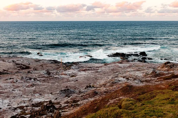 Kayalık bir sahilin yakınındaki bir su kütlesinin manzara görüntüsü. Dalgalar kayalara vuruyor. — Stok fotoğraf