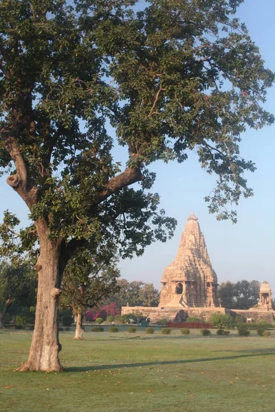 Tiro vertical de un edificio del templo en Khajuraho, India rodeado de árboles verdes bajo el cielo azul —  Fotos de Stock