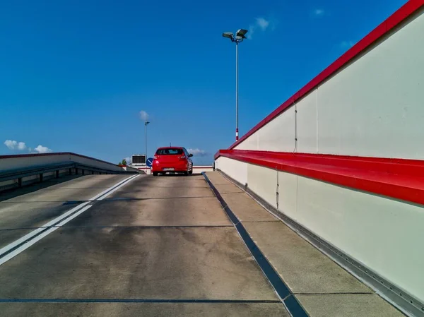Горизонтальный снимок красной машины в движении по шоссе под облачным небом — стоковое фото