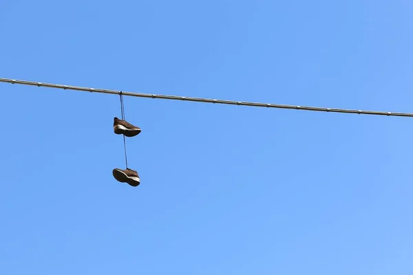 Colpo basso di un paio di scarpe appese a un cavo con il cielo blu mozzafiato sullo sfondo — Foto Stock