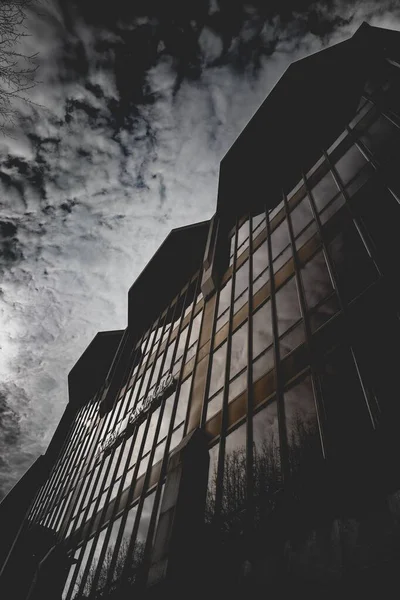Balança de cinza vertical de nuvens de tirar o fôlego refletida em um edifício com janelas de espelho — Fotografia de Stock
