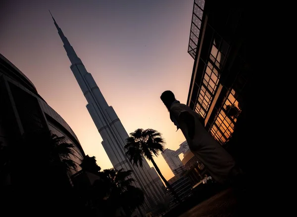 Foto de baixo ângulo de uma pessoa em pé perto do hotel Burj Khalifa durante o pôr do sol em Dubai, Emirados Árabes Unidos — Fotografia de Stock